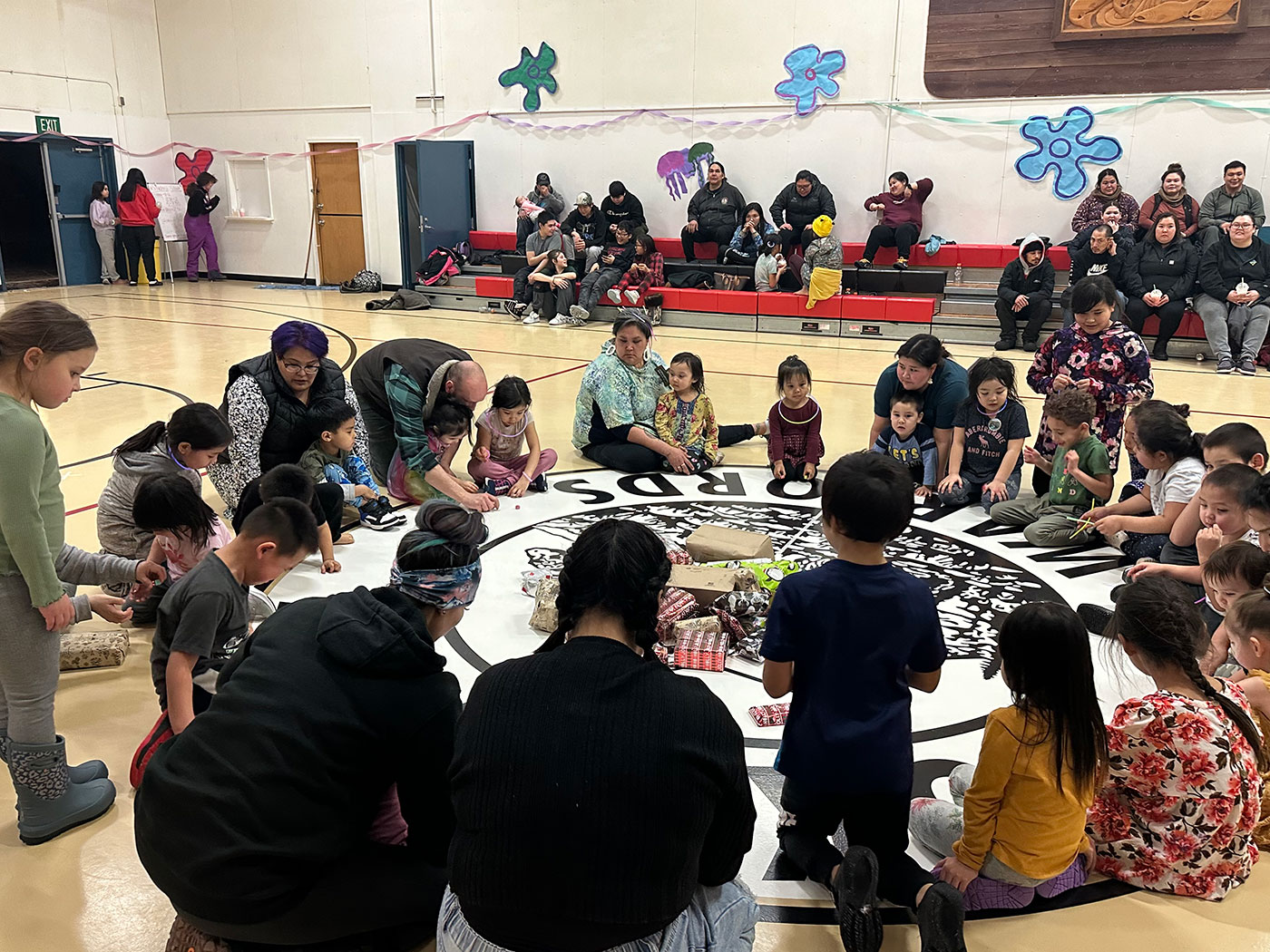 Kids sitting in a circle opening gifts in the gym