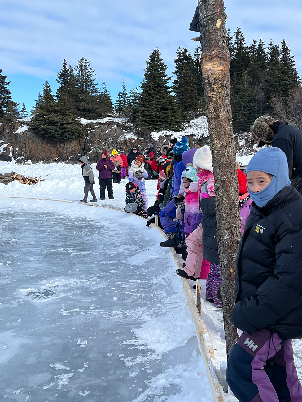 Kids outside in snow gear next to ice