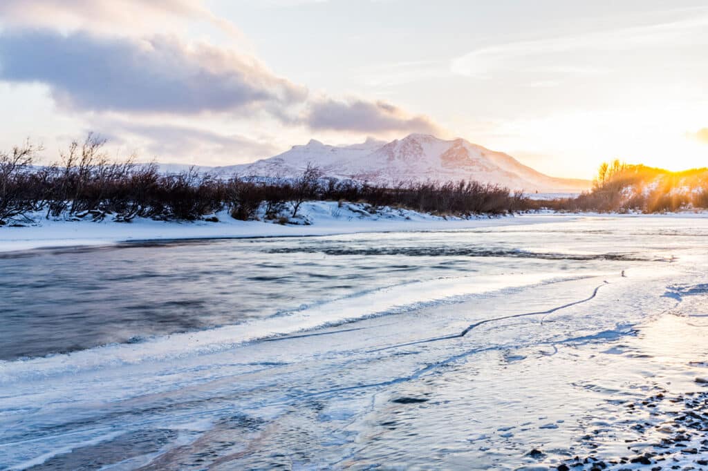 Icy river with snow-covered mountains in the background